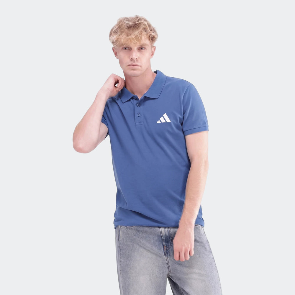A young man with blonde hair models a stylish blue Sportswear Slim Pique Polo Shirt, paired with light-wash denim jeans,
