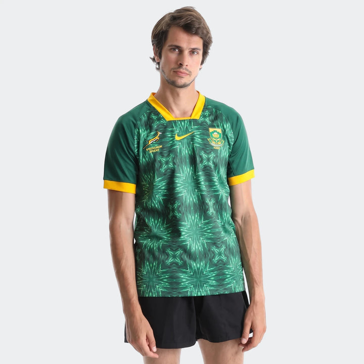 Male model wearing a green and yellow patterned Springbok Rugby short sleeve home jersey and black shorts, front view.