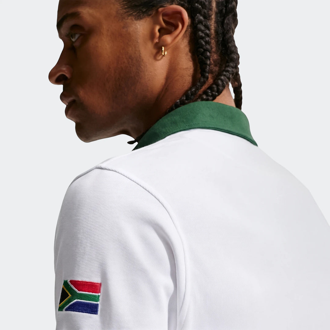 Close-up of a man wearing a white Springboks Away Nike long-sleeve rugby jersey with a green collar and a South African flag