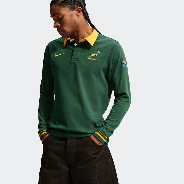 Springboks Home Mens Nike long sleeve rugby jersey in dark green with yellow collar and striped cuffs, worn by a man.