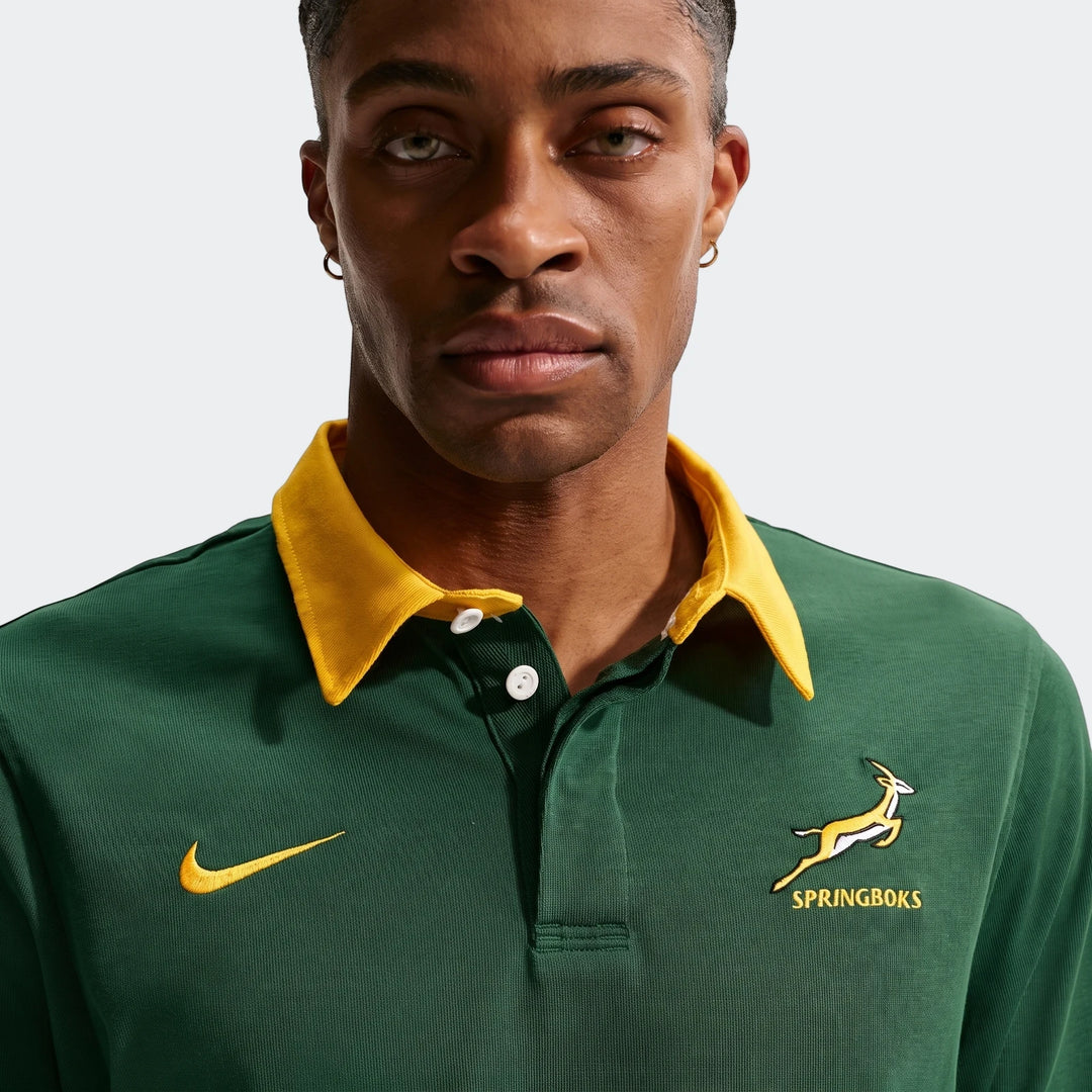Close-up of a man wearing a green Springboks Home Nike long sleeve rugby jersey with a yellow collar and white buttons.