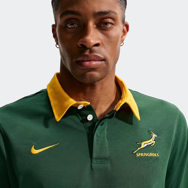 Close-up of a man wearing a green Springboks Home Nike long sleeve rugby jersey with a yellow collar and white buttons.