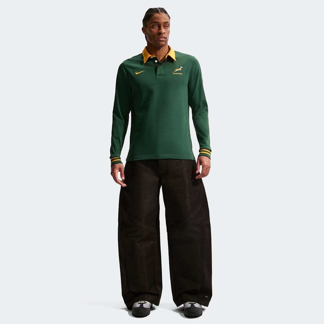 Springboks Home Mens Nike Long Sleeve Rugby Jersey in green, worn by a model with black wide-leg pants and sneakers.