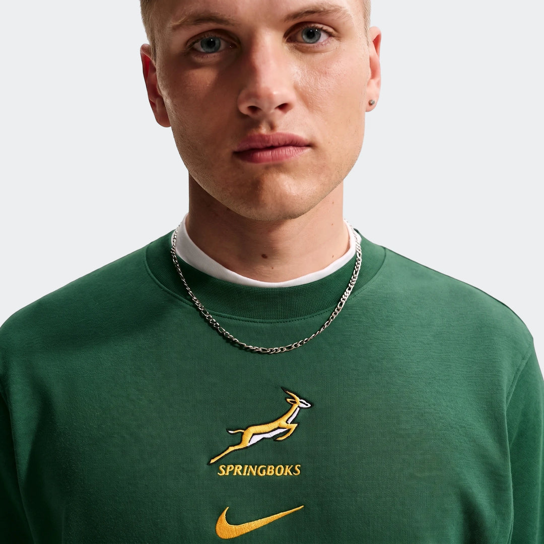 Close-up of a man wearing a dark green Springboks Men's French Terry Crew sweatshirt, featuring embroidered Springbok and