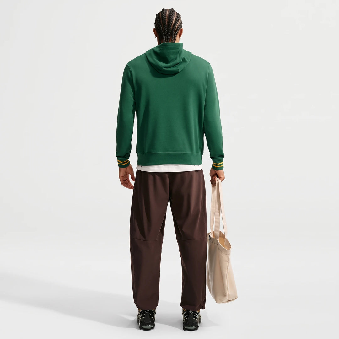 Springboks Men's Nike Hoodie in green, worn by a man with braided hair, seen from the back, holding a tote bag.