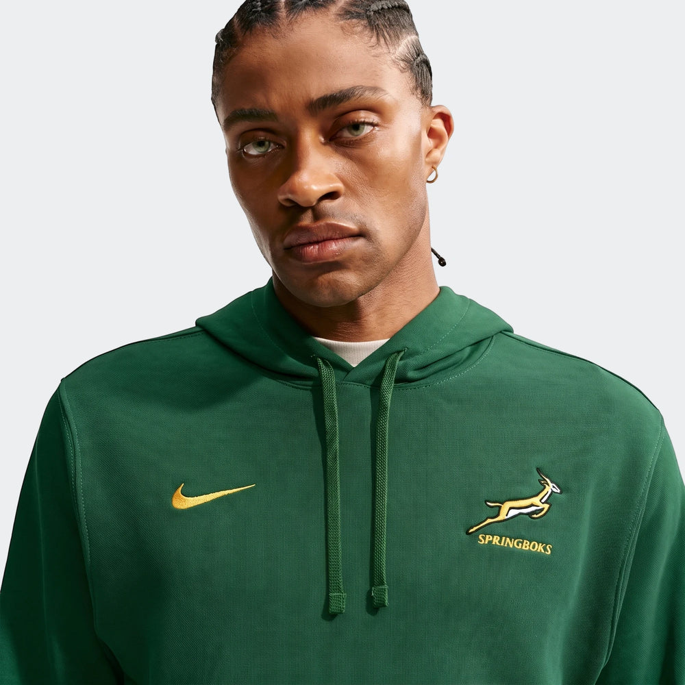 Front view of a Black man wearing a dark green Springboks Men's Nike hoodie with a yellow swoosh and springbok logo.