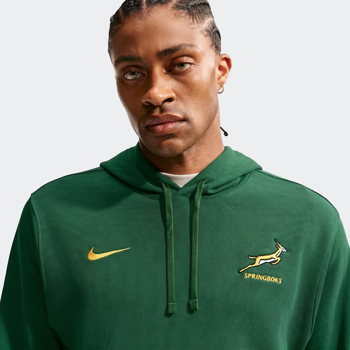 Front view of a Black man wearing a dark green Springboks Men's Nike hoodie with a yellow swoosh and springbok logo.