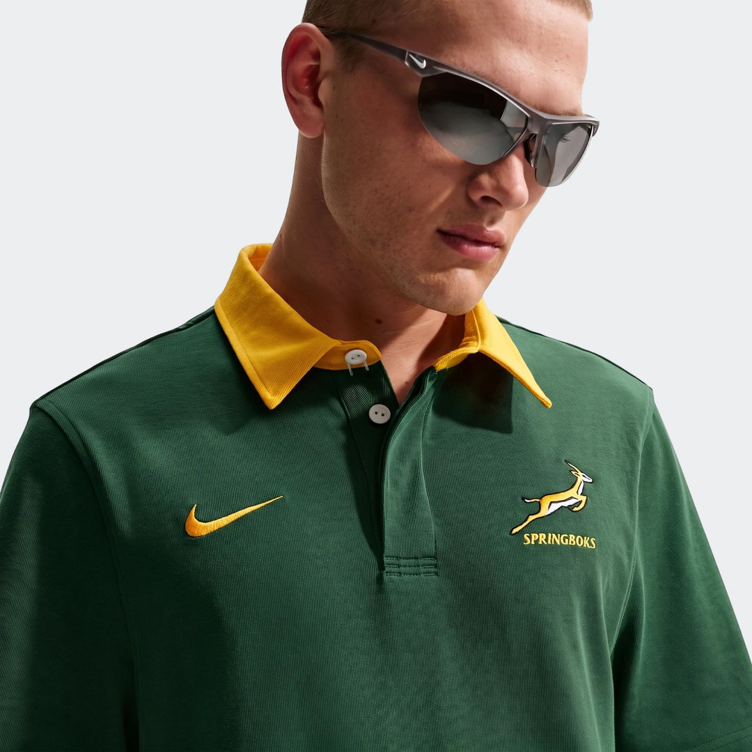 Close-up of a man wearing a dark green Springboks Men'S Rugby Home Short-Sleeve Jersey with a yellow collar, Nike swoosh,
