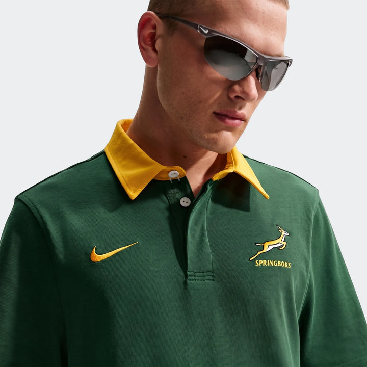 Close-up of a man wearing a dark green Springboks Men'S Rugby Home Short-Sleeve Jersey with a yellow collar, Nike swoosh,