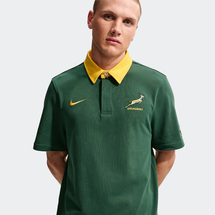 Front view of a male model wearing a dark green Springboks Men's Rugby Home Short-Sleeve Jersey with a yellow collar and