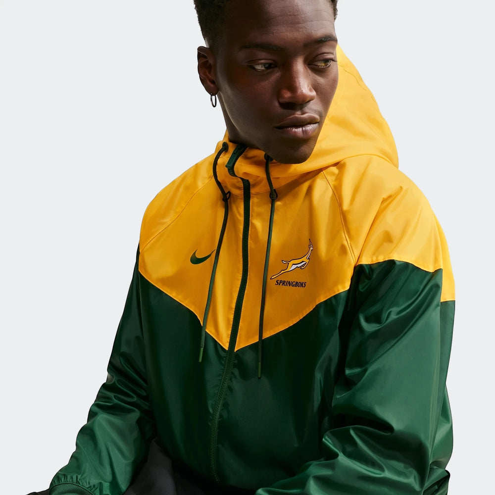 A male model wears a yellow and green Springboks Nike Windrunner hooded jacket, shown from the chest up, looking to the side.