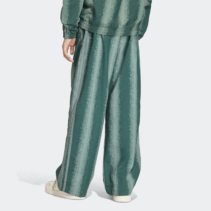 Sst Loose Track Pants in dark green with light green stripes, worn by a person from the back with white sneakers.