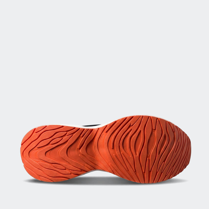 Bottom view of Stelio black and orange sneakers showing a vibrant orange outsole with a distinctive wavy traction pattern.