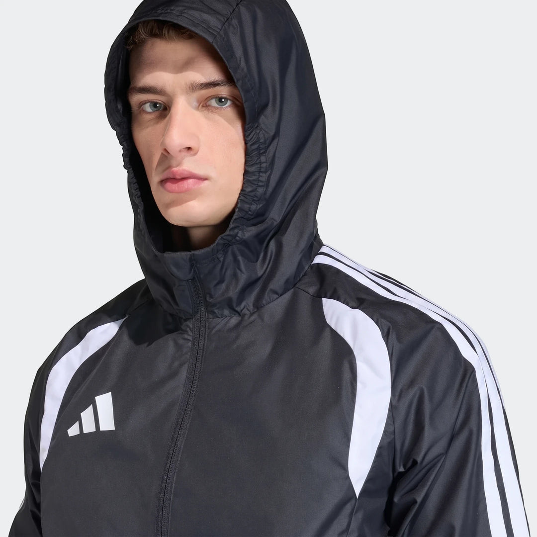 Man wearing black Adidas Tiro 26 Competition All-Weather Jacket with white stripes and hood, close-up.
