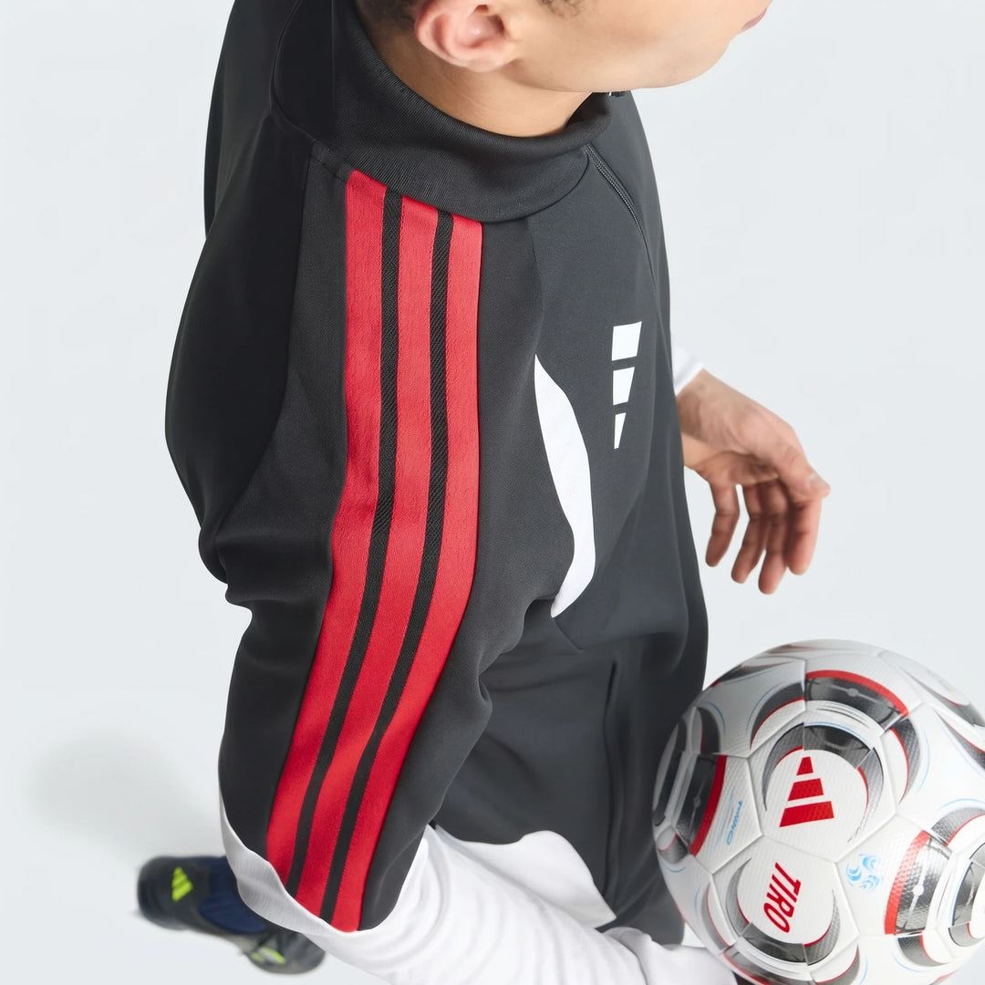 Close-up of a person wearing a black Tiro 26 Competition Training Jacket featuring distinctive red sleeve stripes, posing