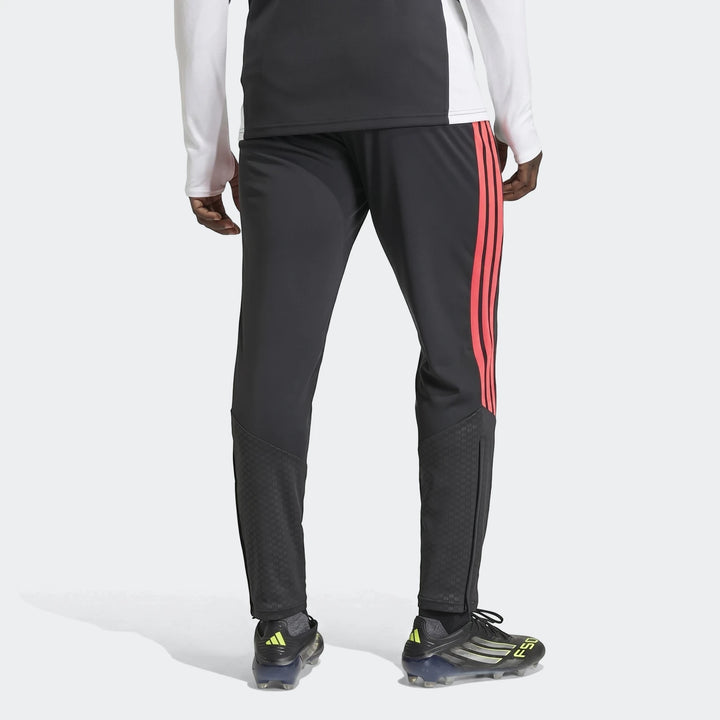 Men's dark grey Tiro 26 Competition Training Pants with vibrant coral side stripes, worn from a back view with soccer cleats.
