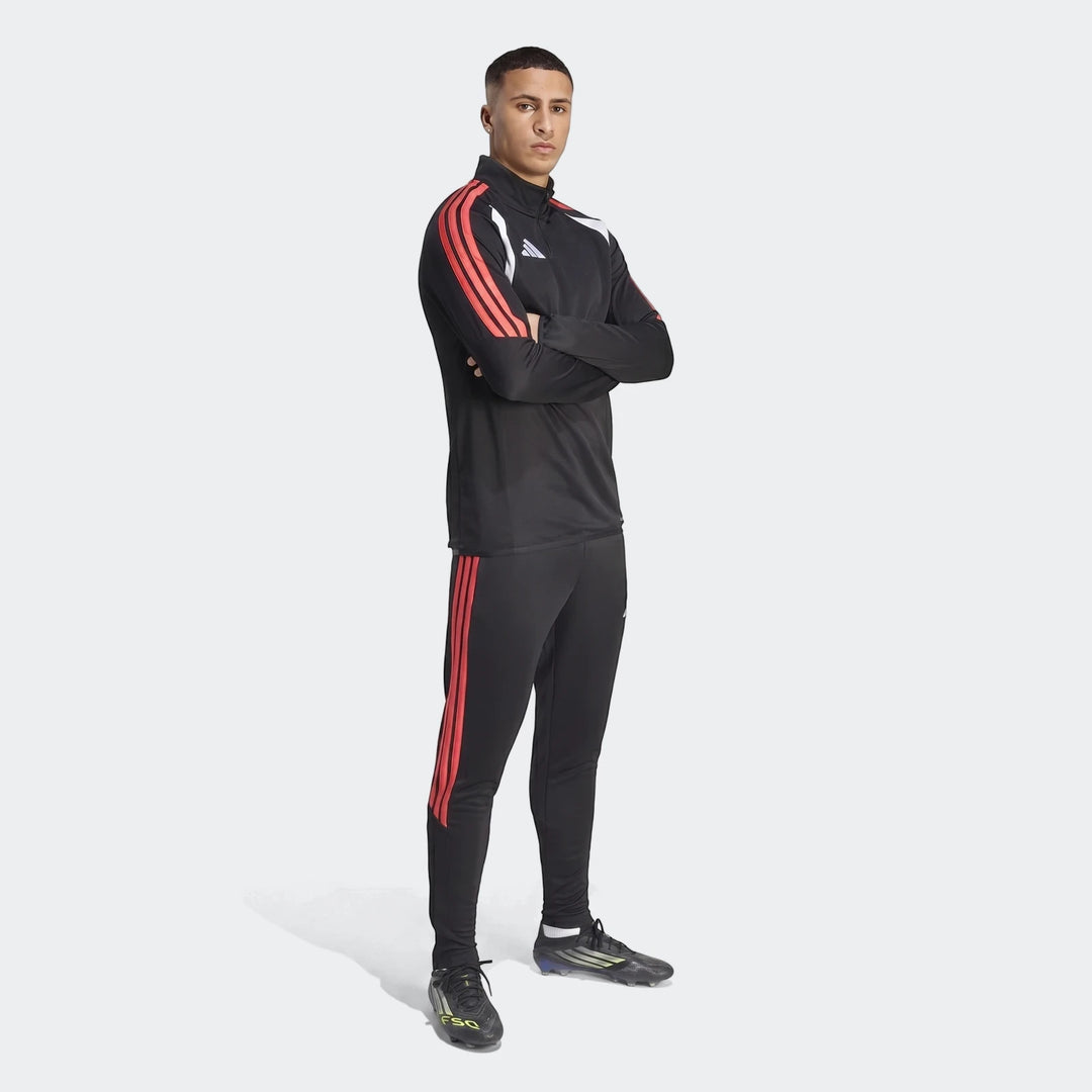 Male model wearing a black Tiro 26 League training tracksuit with red stripes and black football boots, full body view.
