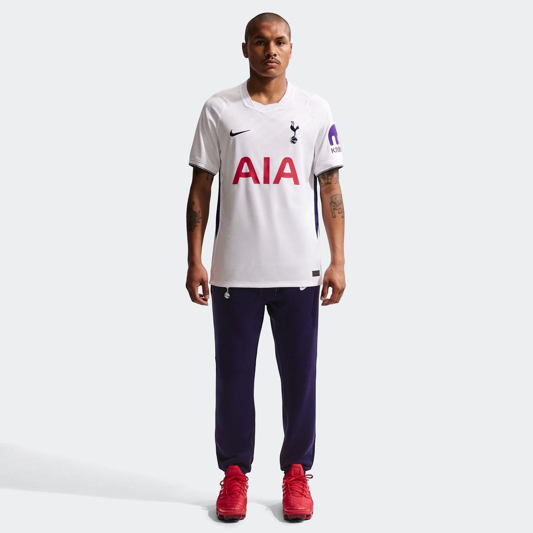 Male model in white Tottenham Hotspur 2026/27 Stadium Home Nike Dri-Fit Soccer Replica Jersey, dark blue pants, and red