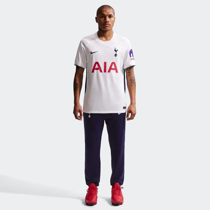 Male model in white Tottenham Hotspur 2026/27 Stadium Home Nike Dri-Fit Soccer Replica Jersey, dark blue pants, and red