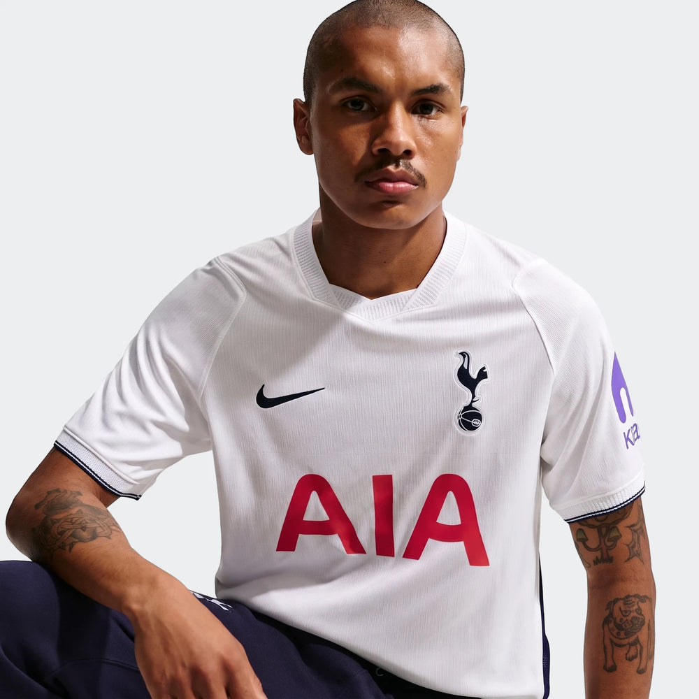 Male model wearing a white Tottenham Hotspur 2026/27 Nike Dri-Fit home soccer jersey with red 'AIA' sponsor.