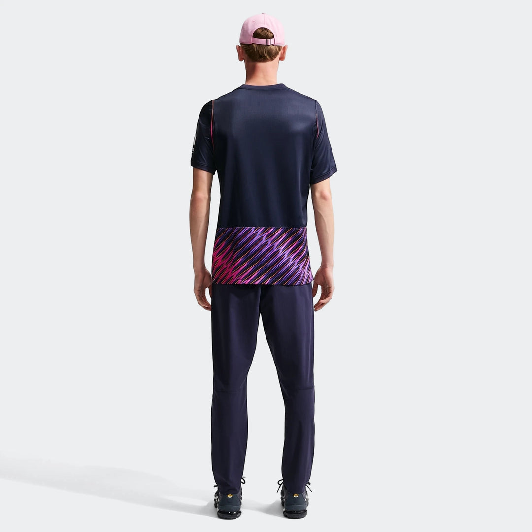 Back view of male model in navy Tottenham Hotspur 2026/27 Stadium Away Nike Dri-Fit soccer jersey and track pants.