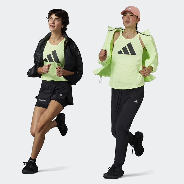 Two women in Adidas running apparel; one wears black shorts and jacket, the other in a pink cap, lime green jacket and black