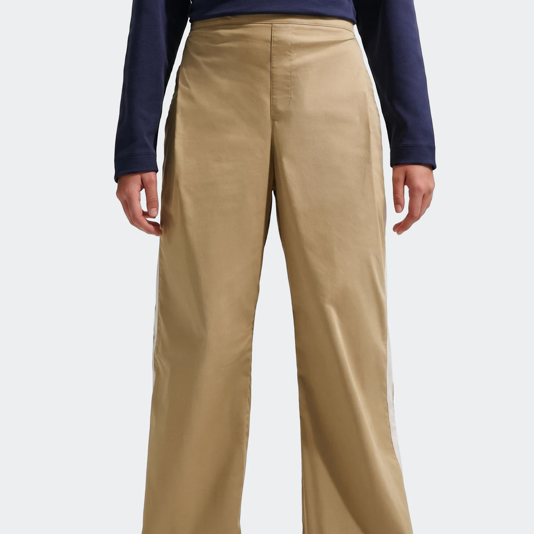 A person models U=G Nsw Wvn Pant Parachute Brown Pants, featuring a wide-leg cut and white side stripes.