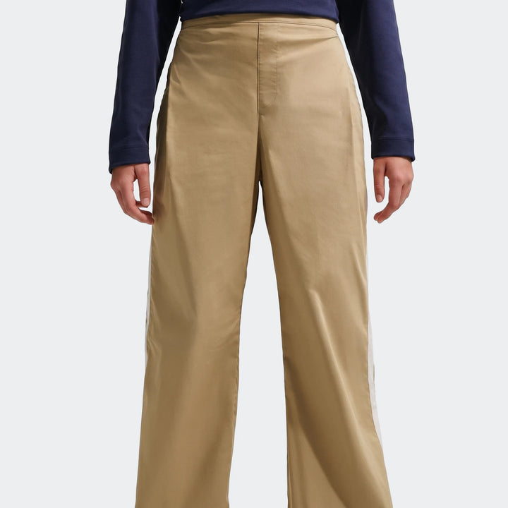 A person models U=G Nsw Wvn Pant Parachute Brown Pants, featuring a wide-leg cut and white side stripes.