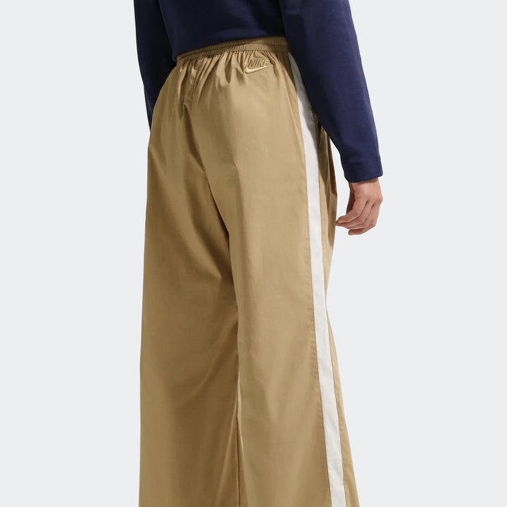 U=G Nsw Wvn Parachute Brown Pants with a white side stripe, worn by a model and viewed from the back.