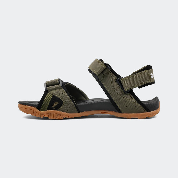 Ula Green Sandals, side view, featuring green webbing straps, black footbed, and a brown rubber sole.