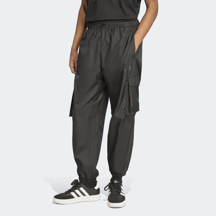 Person wearing black Utility Woven Pants with cargo pockets and black and white Adidas sneakers, front view.