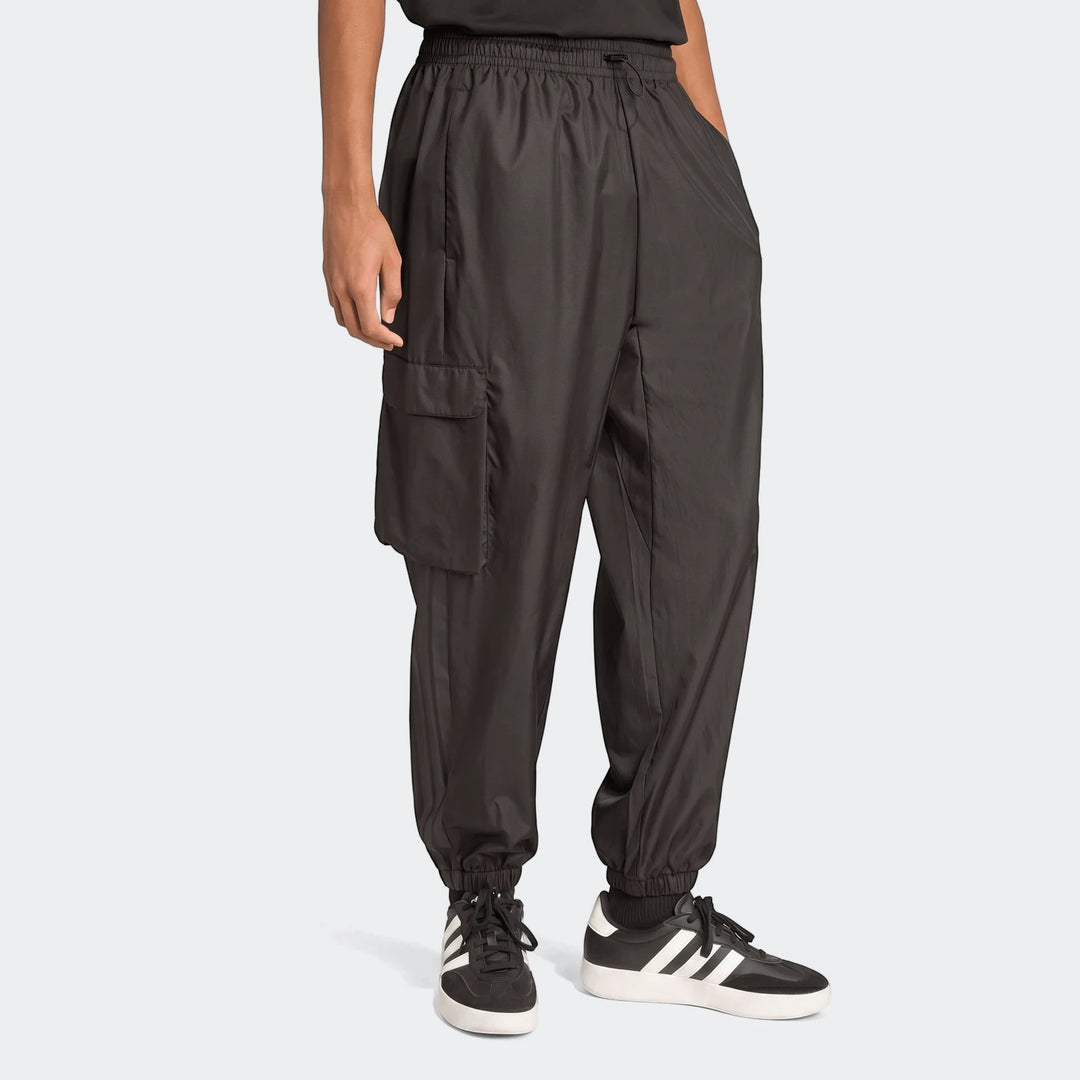 Male model wearing black utility woven pants with a cargo pocket and black sneakers. Side view of the comfortable and