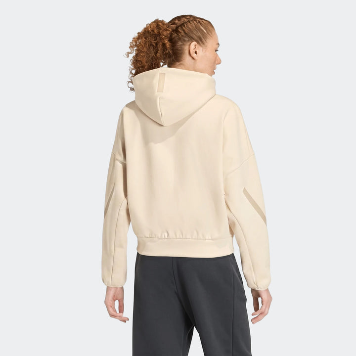 Rear view of a woman wearing a beige W Z.N.E Fz Jacket hoodie with dark pants, showcasing the design.