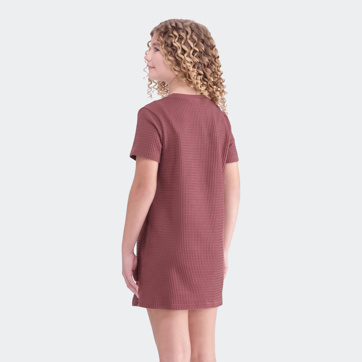 Young girl in a reddish-brown waffle dress with short sleeves, shown from the back, highlighting the textured fabric.