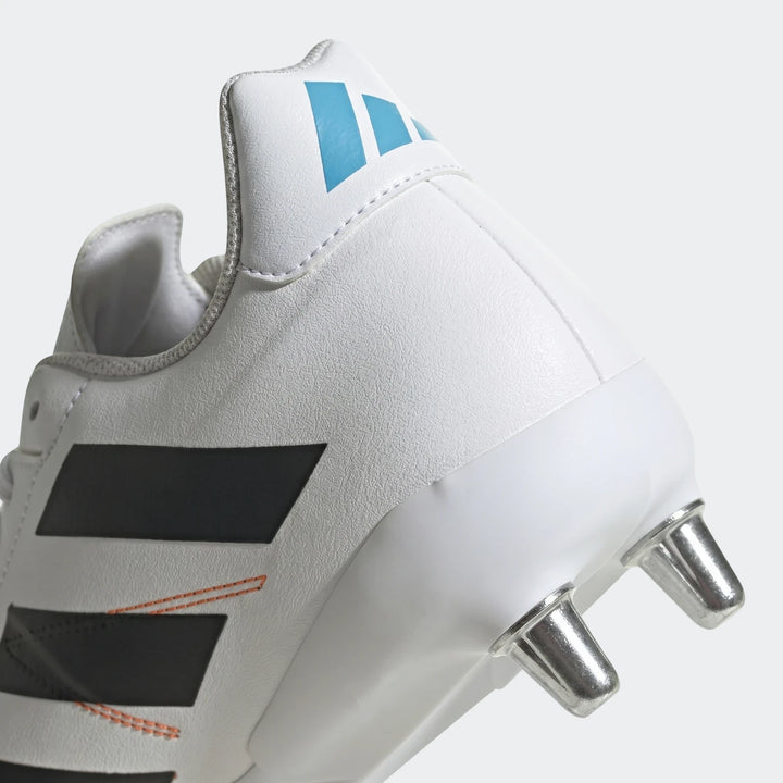 Close-up rear and side view of a white Adidas Kakari Elite SG rugby boot featuring black stripes and metallic studs.
