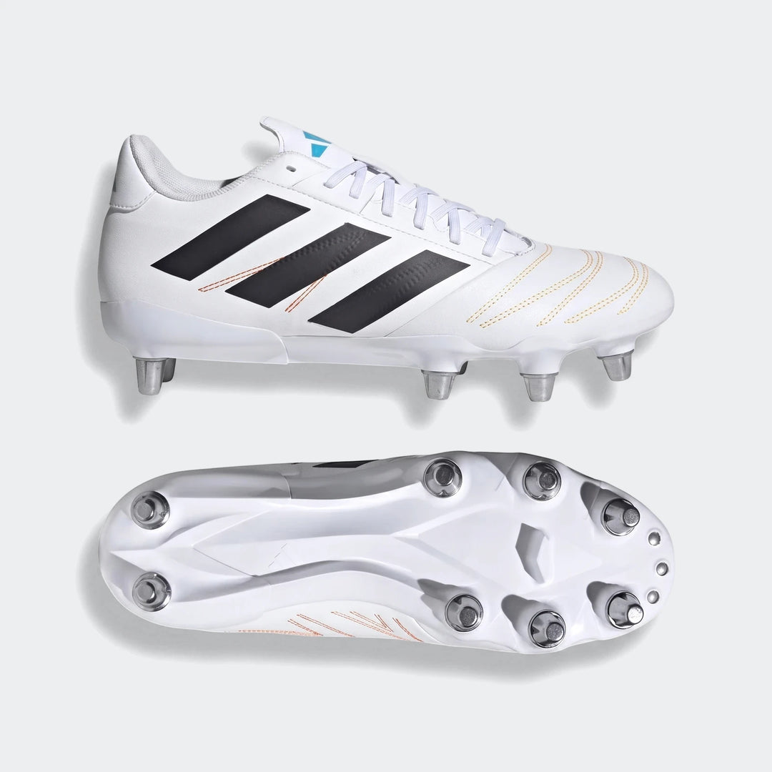 Pair of white Adidas Kakari Elite SG rugby boots with black stripes and orange stitching, shown from two angles.