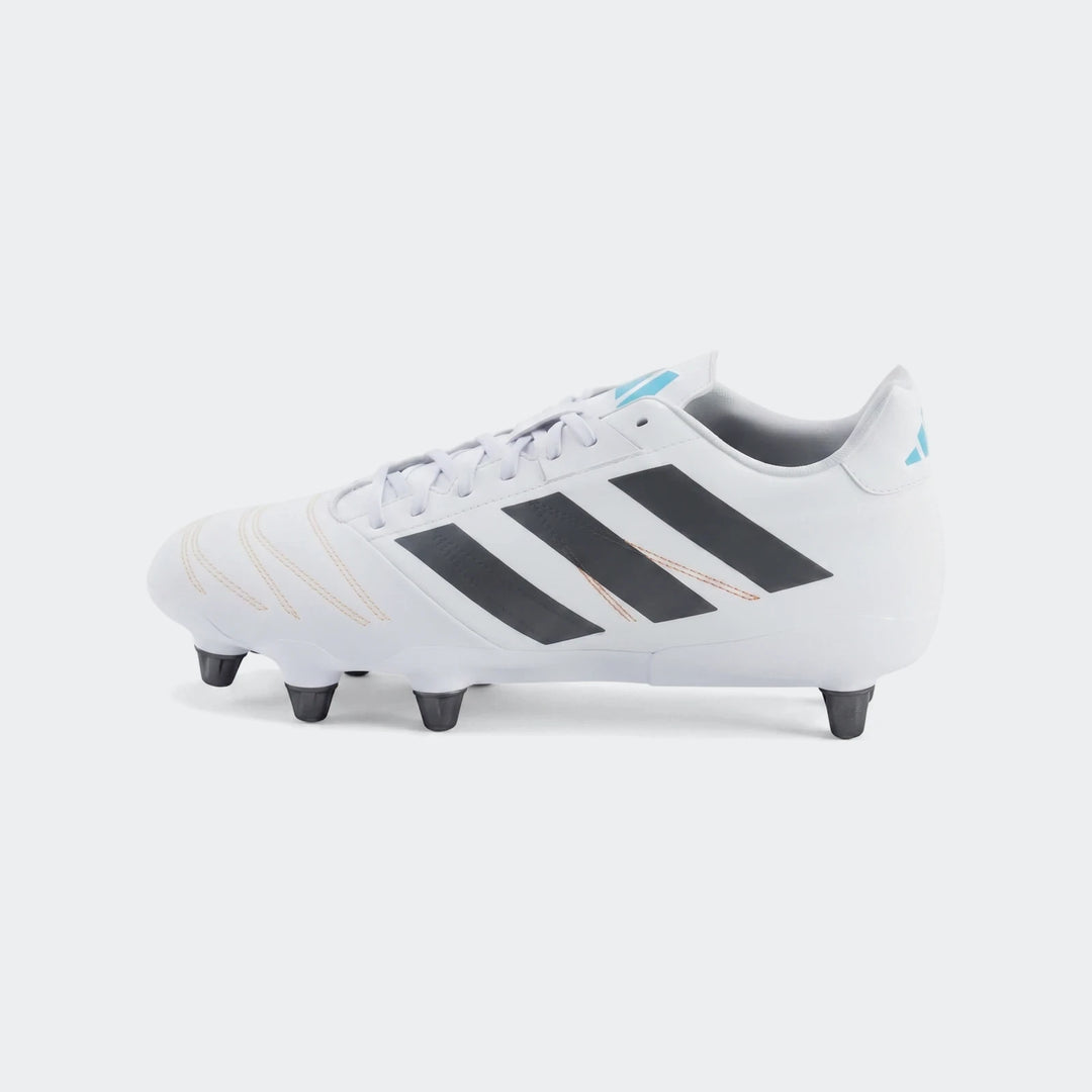 White Adidas Kakari Elite Sg Rugby Boots with black stripes and light blue accents, displayed on green grass in a side view.