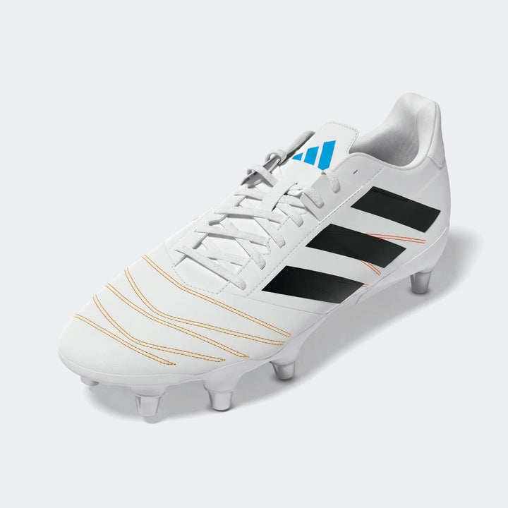 White Adidas Kakari Elite SG rugby boots with black three stripes, a blue logo, and orange stitching accents, shown at a