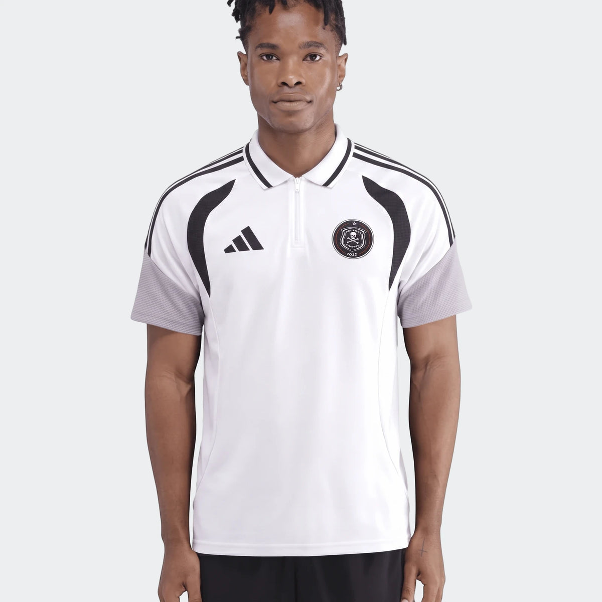 Male model wearing a white Adidas Op Tiro26C Polo shirt with black stripes and Orlando Pirates badge, front view.