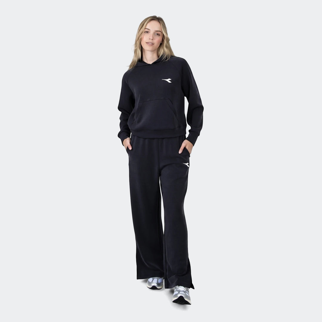 Woman wearing a black Michelle Hoodie with a front pocket and matching wide-leg sweatpants, paired with silver sneakers.