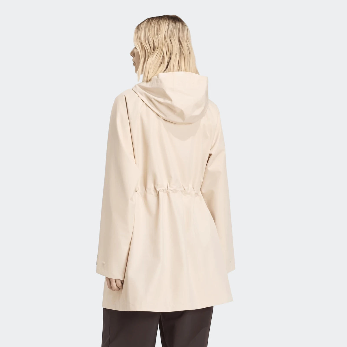 Back view of a woman wearing a light beige City Rain Parka with a hood and drawstring waist, on a white background.