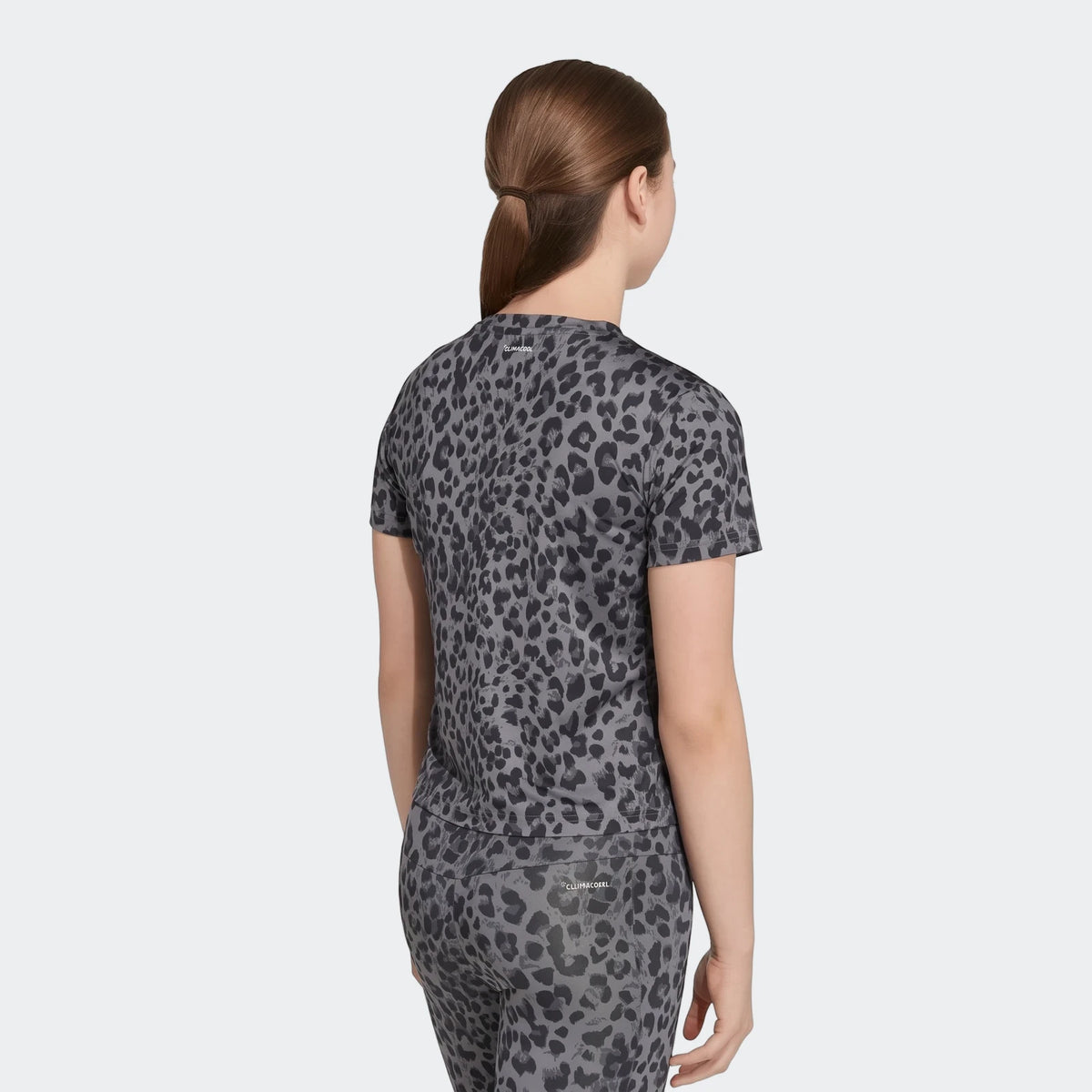 Woman wearing a gray leopard print short-sleeved sport t-shirt and matching leggings, shown from the back.