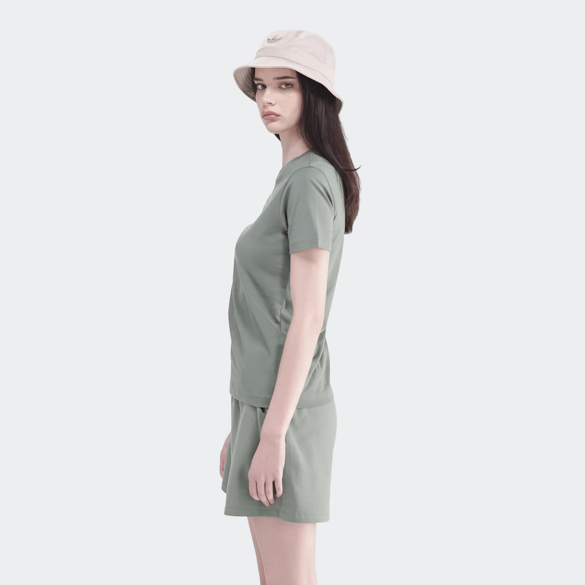 Young woman in a sage green short-sleeve t-shirt and matching shorts set, accessorized with a beige bucket hat.