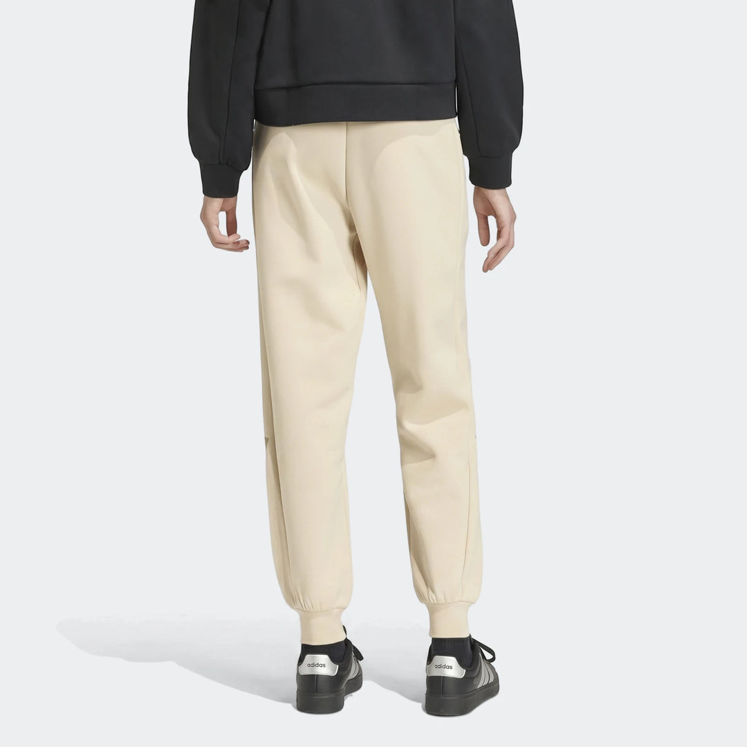 Women's Adidas W Z.N.E Pt Beige Trackpants, shown from the back on a model, paired with black Adidas sneakers.