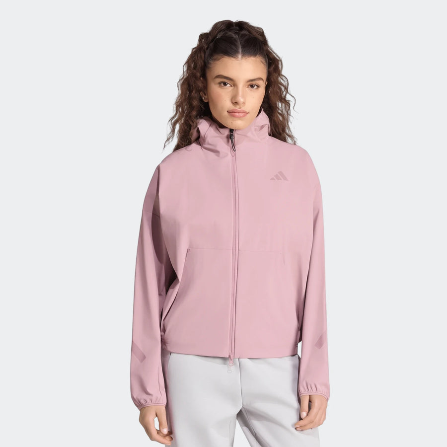 Women's Adidas Z.N.E. Woven Track Top in light pink, featuring a full-zip front, hood, and reflective sleeve stripes.