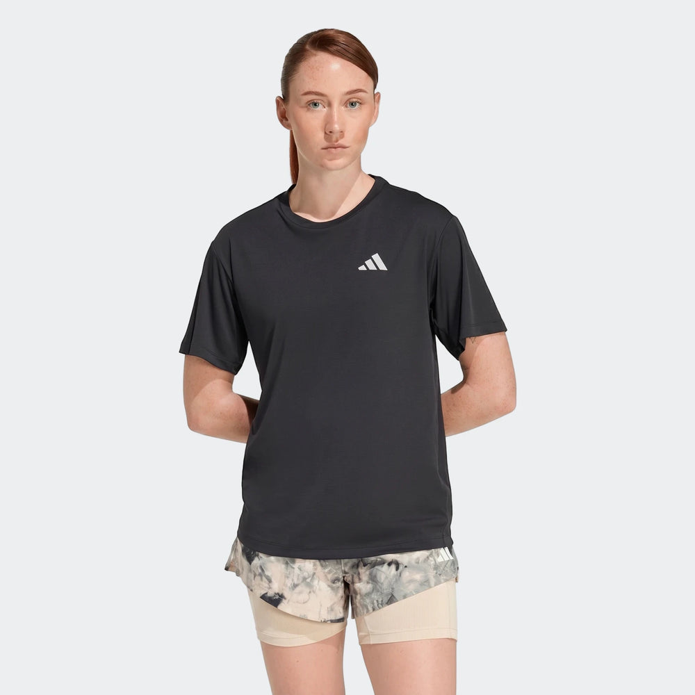Woman wearing a black Adidas Run Essentials T-shirt and patterned running shorts, front view.
