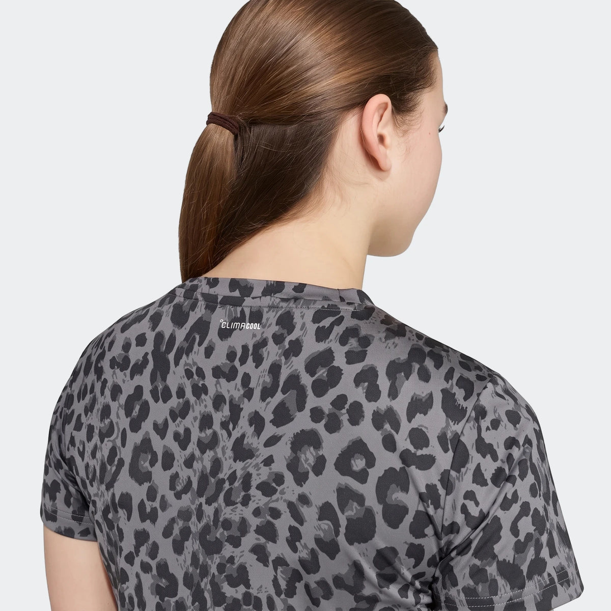 Female model in a gray and black seasonal animal print short-sleeve sport t-shirt, seen from the back, with a 'CLIMACOOL'