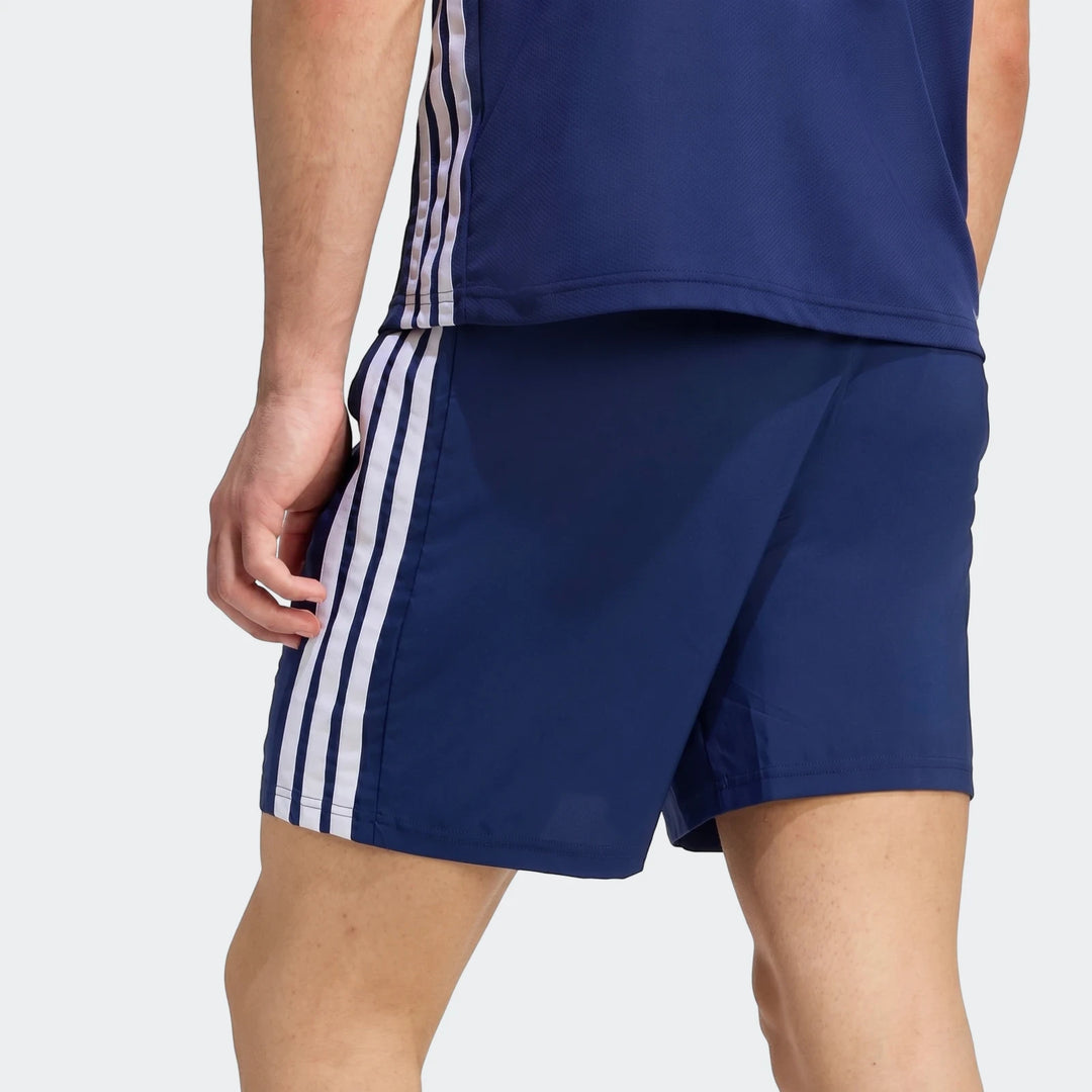 Male model wearing navy blue Workout Essentials Base 3-Stripes Woven Shorts and a matching top, shown from the back-right