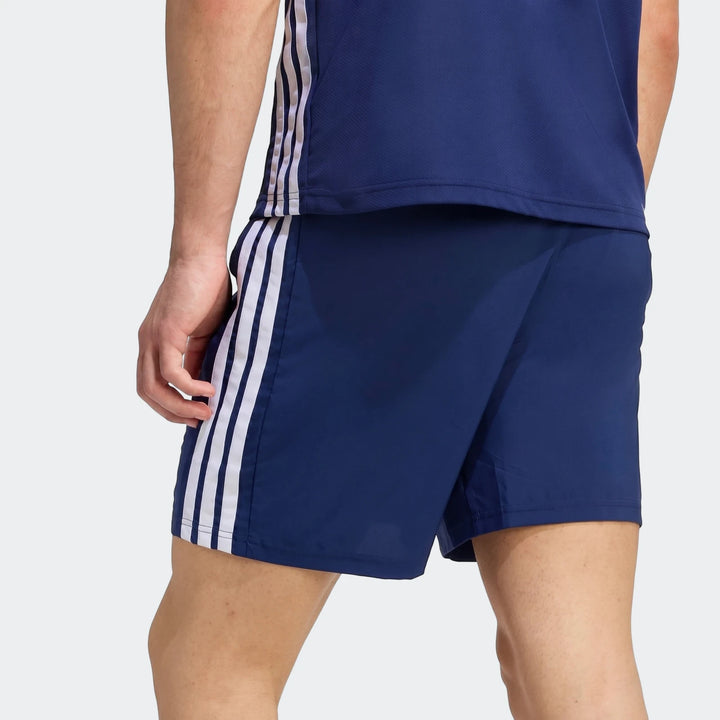 Male model wearing navy blue Workout Essentials Base 3-Stripes Woven Shorts and a matching top, shown from the back-right