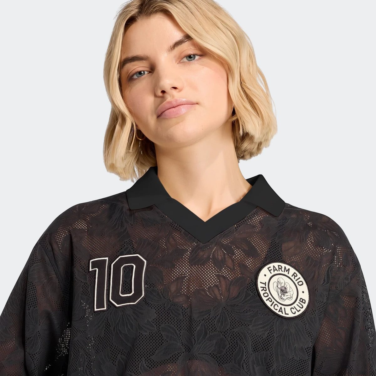 Close-up of a woman wearing a black mesh X Farm Rio Premium Jersey with a white '10' graphic and 'Tropical Club' patch.
